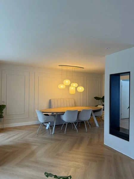 Eetkamer met sierlijsten achter een eettafel en hanglampen